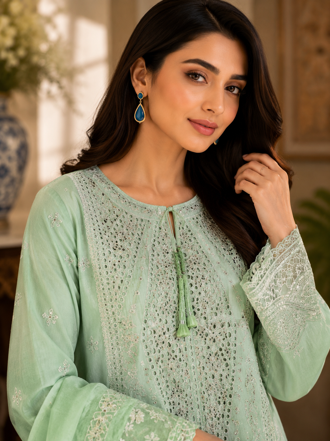 Woman wearing a light green embroidered traditional outfit indoors.